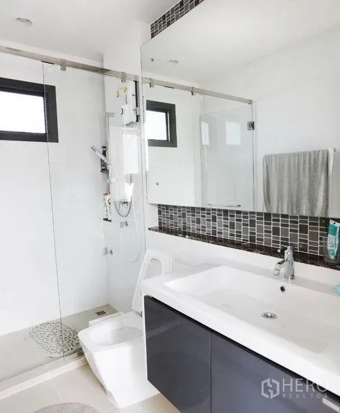 Detached House for rent or sale in Bang Kapi, Bangkok - Contemporary bathroom with glass shower enclosure, vanity and large mirror.