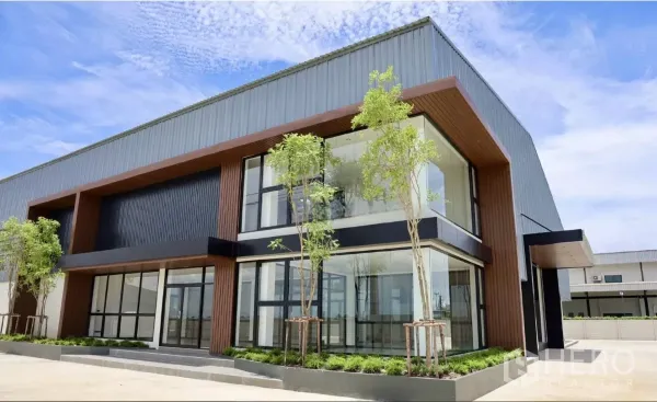 工厂 出租或出售在Phutthamonthon, Nakhon Pathom - 近景展示挑高入口、转角落地玻璃与景观花坛。