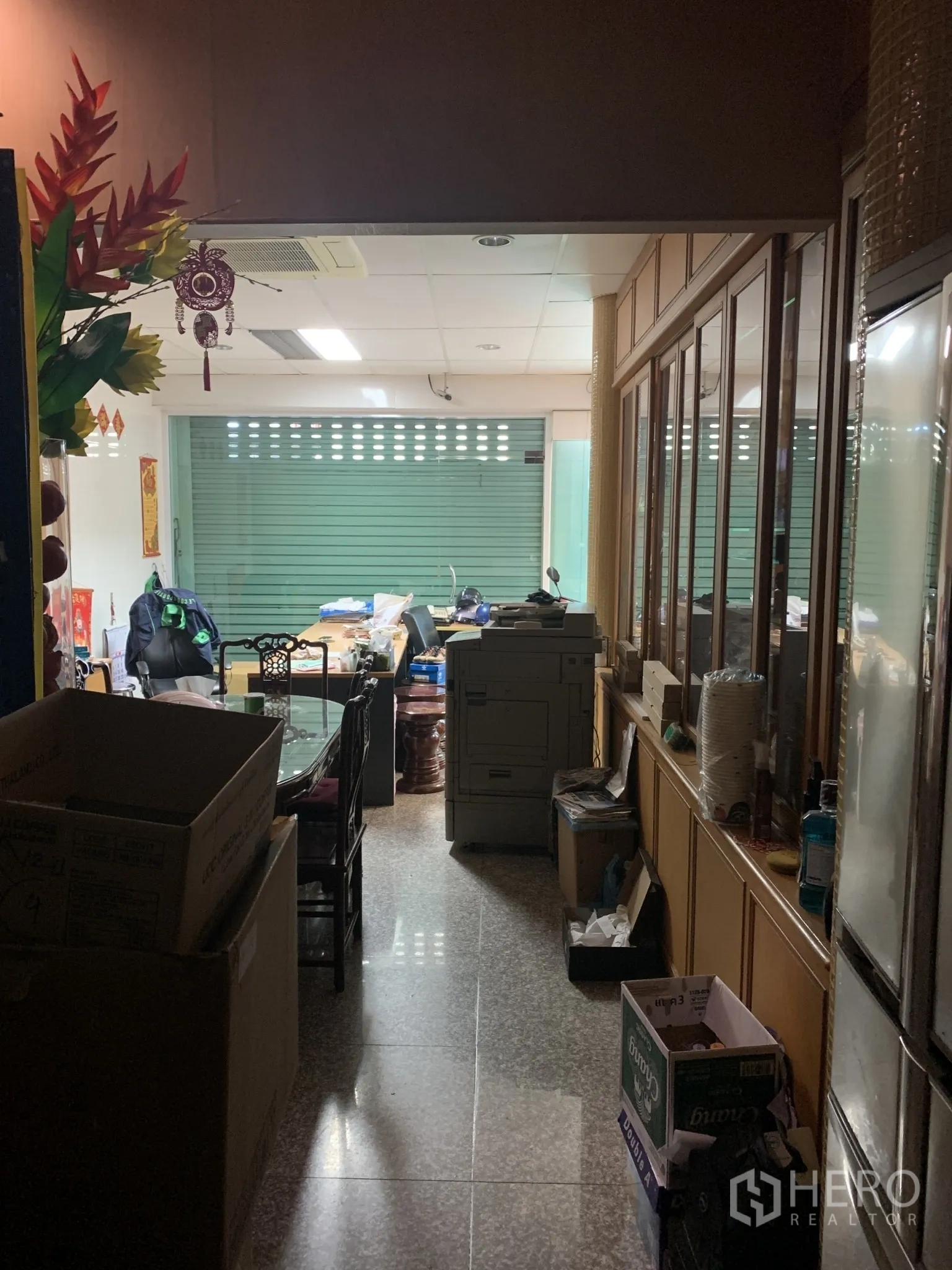 店屋 出售在Pathum Wan, Bangkok - 一层工作区，玻璃隔断、办公桌与前方卷闸门。