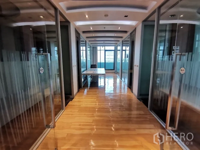 Office Space for rent in Bang Rak, Bangkok - Glass-walled corridor with offices and a central desk facing the windowed terrace.