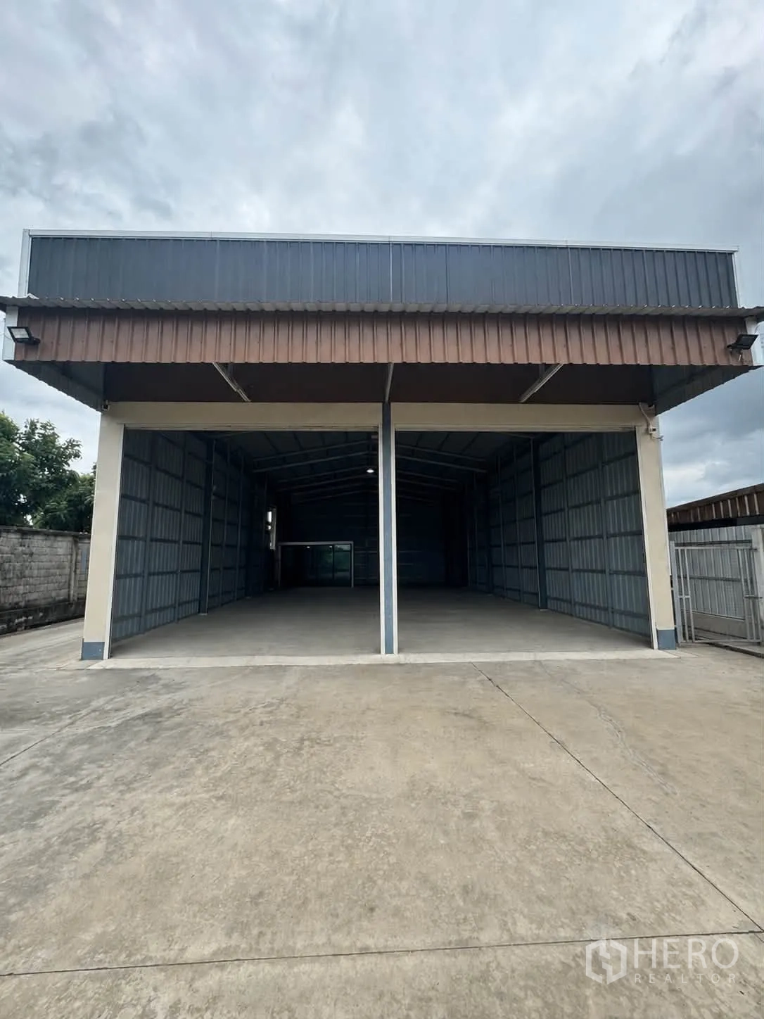 Warehouse for rent in Bang Kruai, Nonthaburi - Front of the warehouse showing two open bays and a wide concrete loading area.