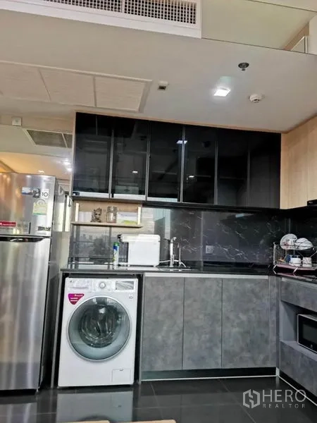 Condominium for rent - Compact kitchen with black marble backsplash, upper cabinets and front-load washer.