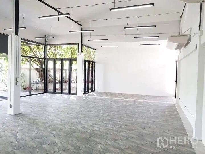 办公空间 出租在Chatuchak, Bangkok - 大开间转角玻璃与花园景观，树荫环绕。