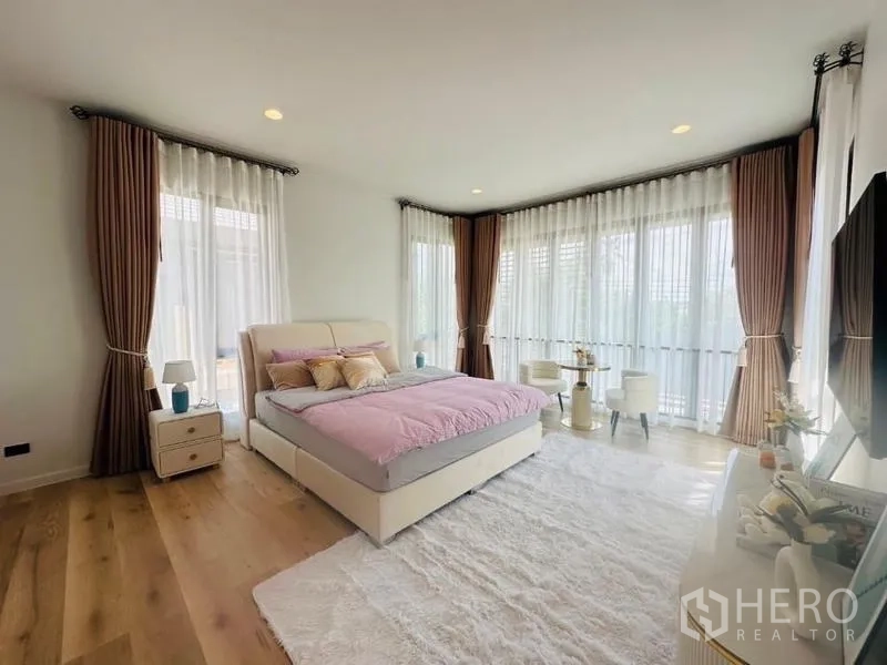 บ้าน ให้เช่าหรือขายในBang Kapi, Bangkok - ห้องนอนใหญ่ มุมหน้าต่างกระจกโค้ง เตียงบุนวม มุมนั่ง และพรมสีขาว.