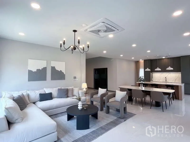 Detached House for rent or sale in Bang Phli, Samut Prakan - Bright open-plan living, dining and kitchen with chandelier, island counter and recessed lighting.