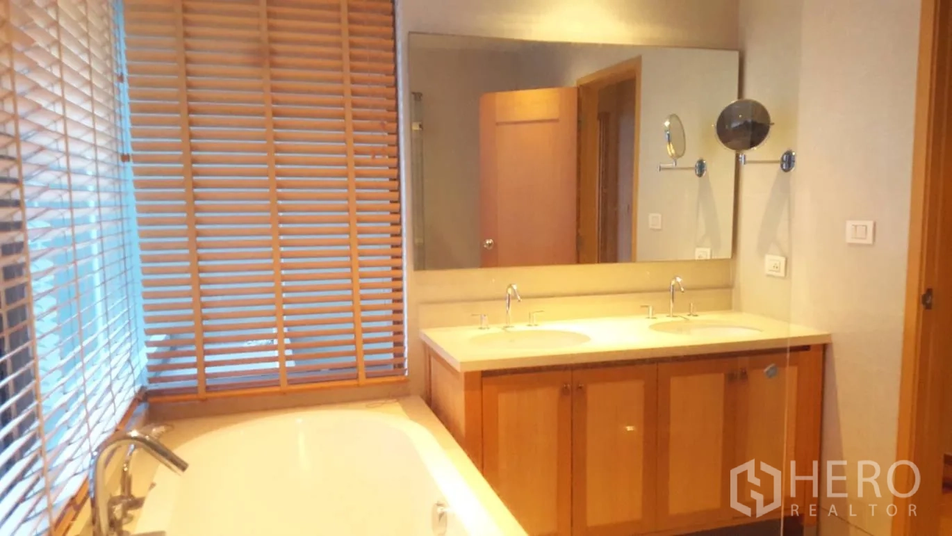 公寓 出租或出售在Khlong Toei, Bangkok - 浴室设窗边浴缸、双洗手台和大镜子。