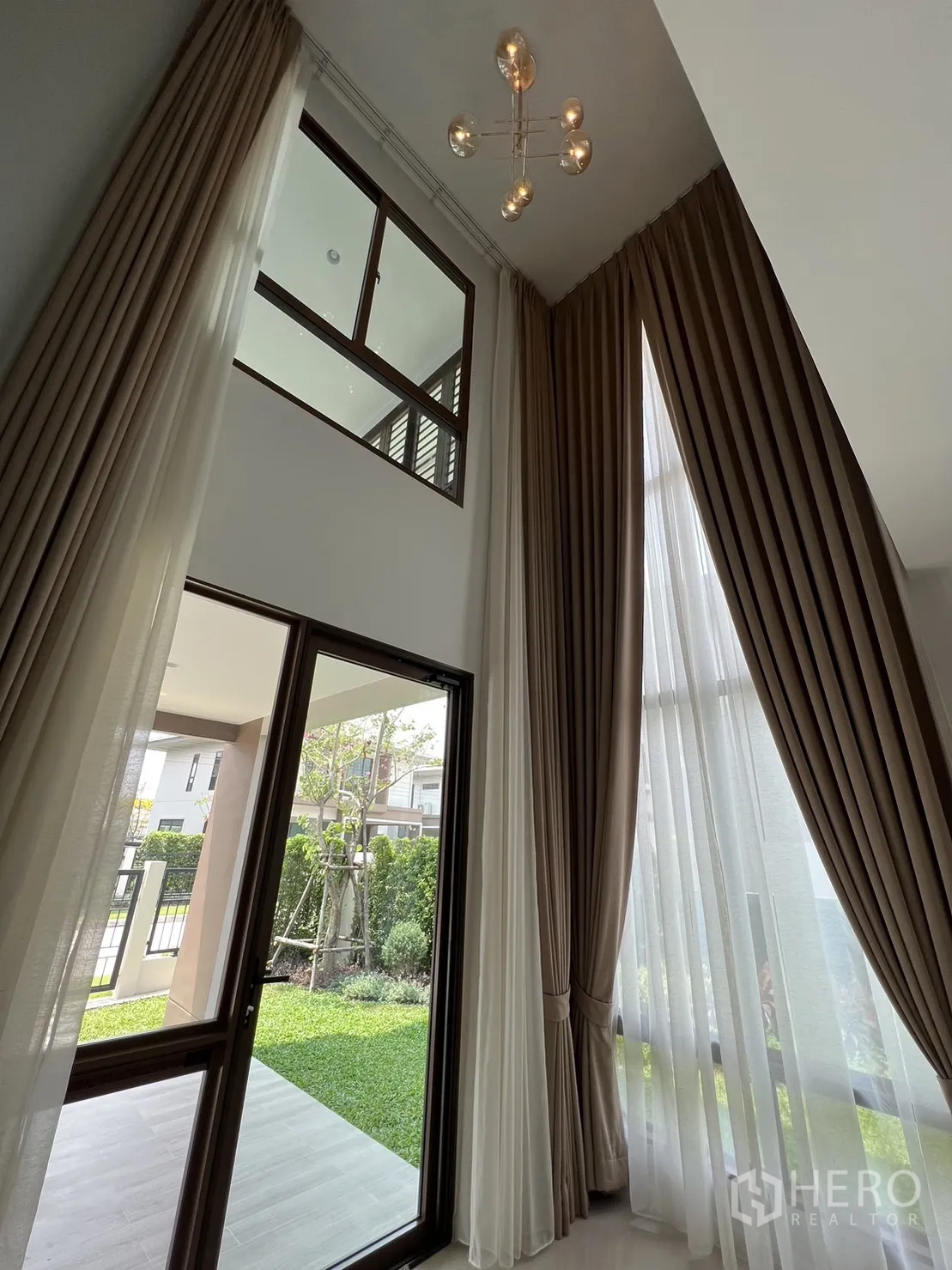 บ้าน ให้เช่าในBang Kapi, Bangkok - ผนังกระจกโถงรับแขกเพดานสูง เปิดออกสู่สนามหญ้าเขียว