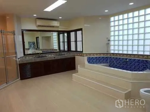 Townhouse for rent in Khlong Toei, Bangkok - Spacious master bathroom with step-up jacuzzi-style tub and glass-block window.