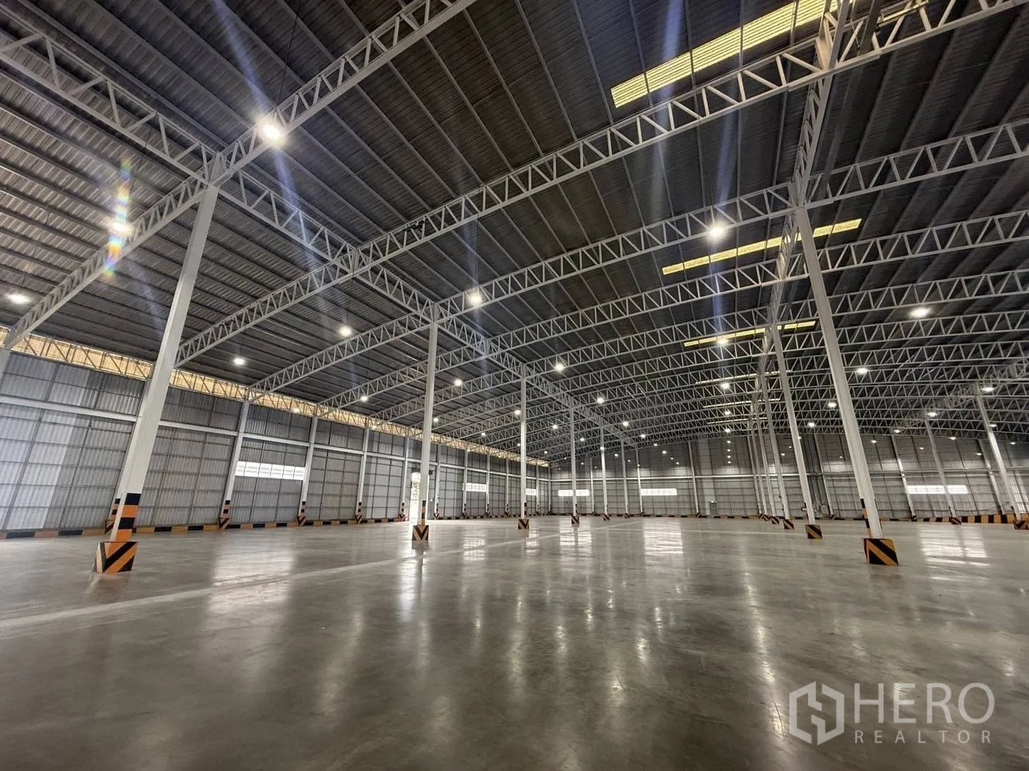 Factory for rent in Si Racha, Chon Buri - Wide-angle view of illuminated warehouse ceiling and open floor area.