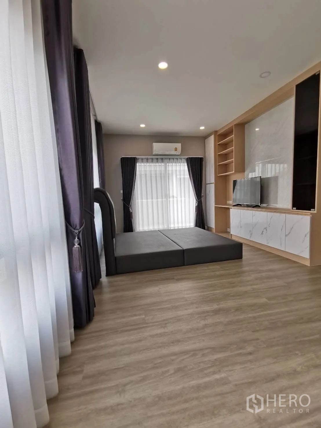 Detached House for rent in Bang Phli, Samut Prakan - Multi-purpose room with floor mattress and marble-look built-in TV cabinet, wide windows, and air conditioning.