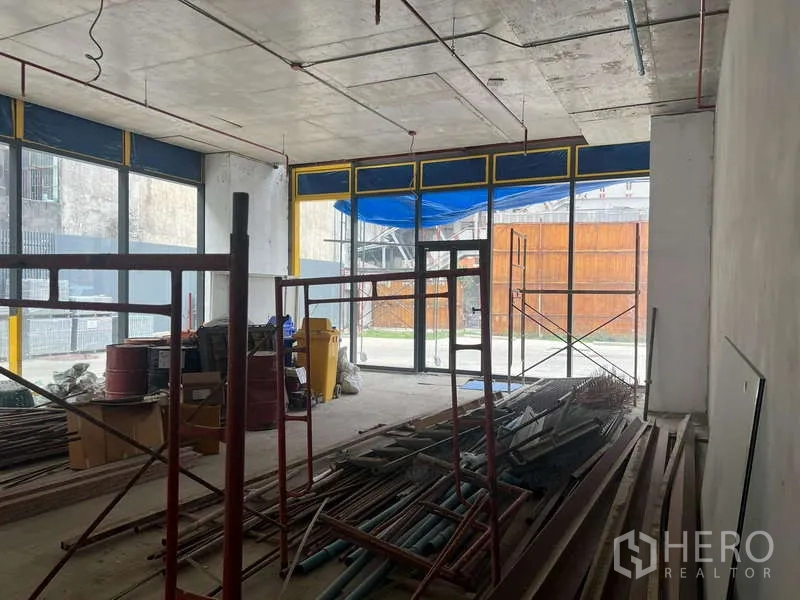 พื้นที่ขายปลีก ให้เช่า - พื้นที่ค้าปลีกแบบโครงเปล่า เพดานสูง กระจกเต็มผนัง ด้านในมีนั่งร้านและวัสดุก่อสร้าง