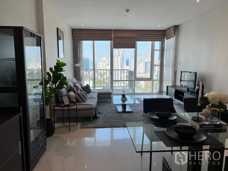 公寓 出租在Watthana, Bangkok - 客厅设L形沙发与茶几，整面窗户尽享天际线景观。