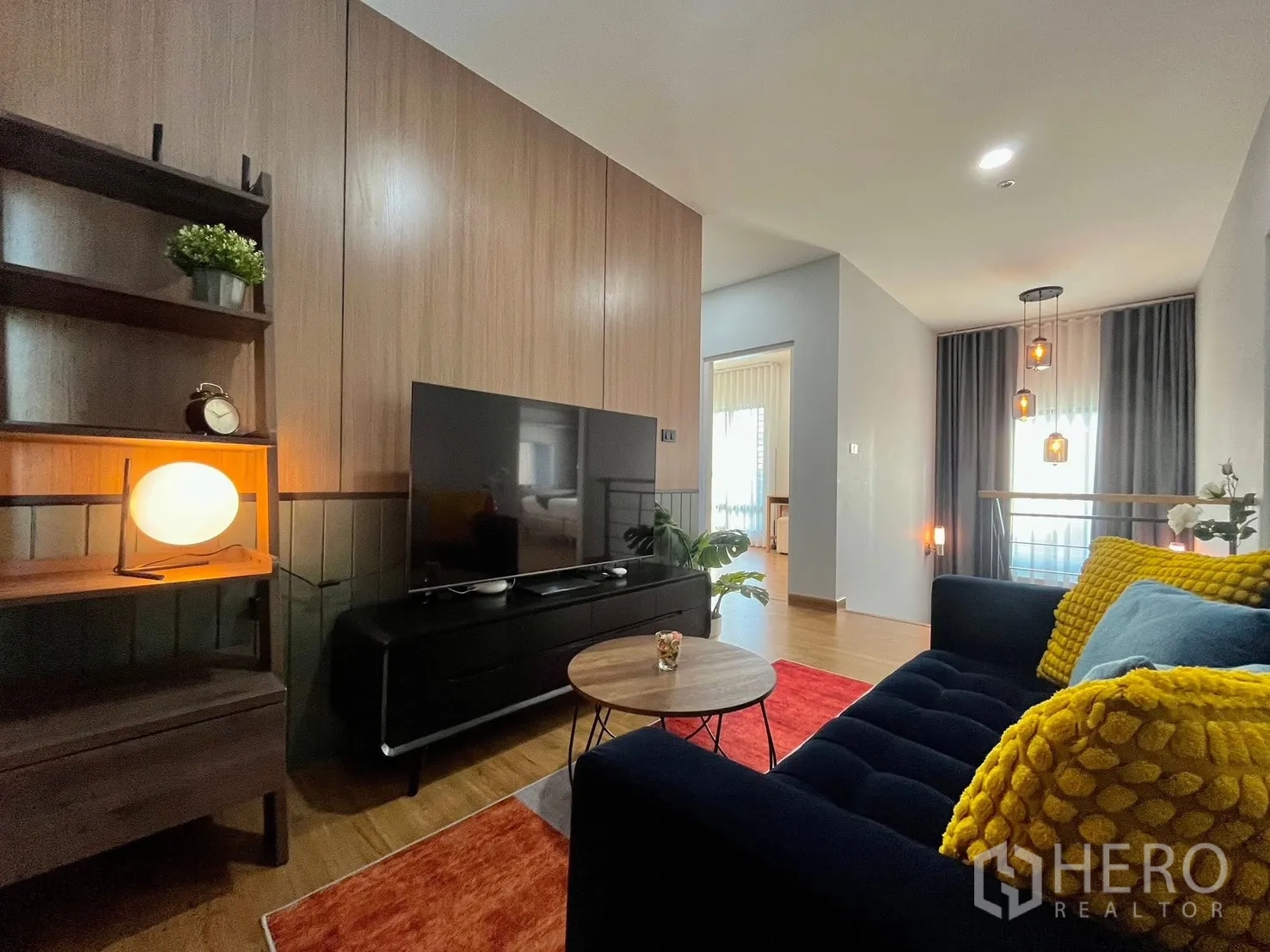 Detached House for rent in Bang Phli, Samut Prakan - Upstairs family lounge with wood paneling, large TV, dark sofa and pendant lighting.