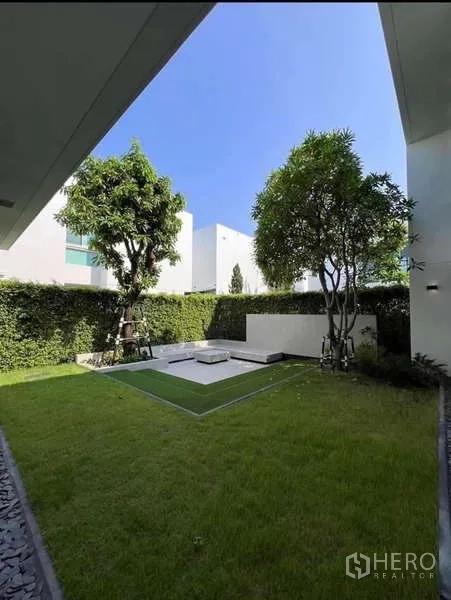 Detached House for sale in Bang Phli, Samut Prakan - Private landscaped garden with lawn, trees and a raised patio bordered by tall hedges.