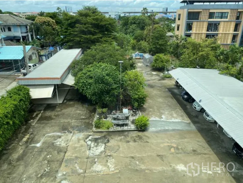 Land for sale in Lat Krabang, Bangkok - Elevated view of a large paved site with carports, trees, and a central planter.