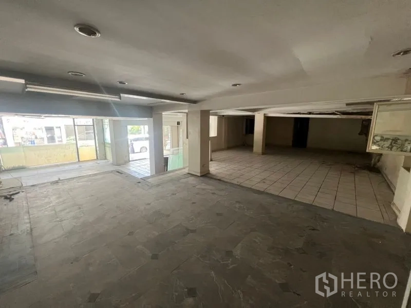 零售空间 出租在Watthana, Bangkok - 开阔店铺内部，立柱与混合瓷砖地面，大窗采光。