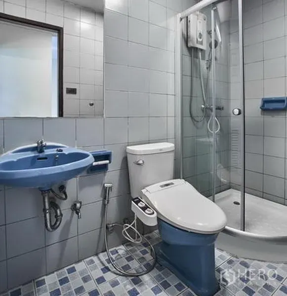 คอนโด ให้เช่าในWatthana, Bangkok - ห้องน้ำปูกระเบื้องพร้อมตู้ชาวเวอร์ กระจก อ่างล้างมือสีน้ำเงิน และโถสุขภัณฑ์พร้อมสายชำระ