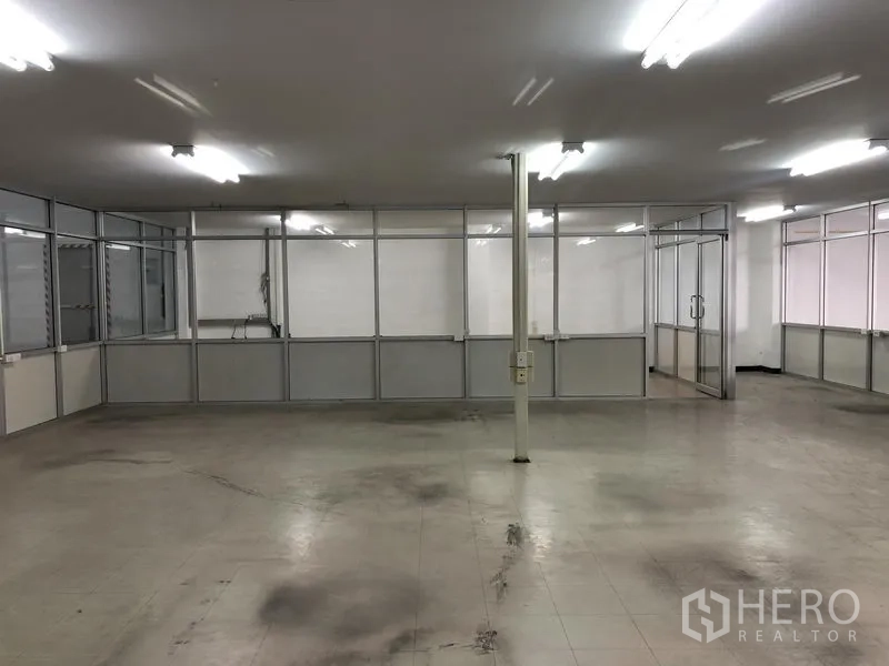 货栈 出租在Nonthaburi - 仓库内的玻璃隔断办公室，荧光照明与瓷砖地面。