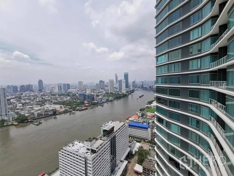 Condominium for rent in Bang Kho Laem, Bangkok - High-floor view of the Chao Phraya River beside a modern riverside condominium facade.