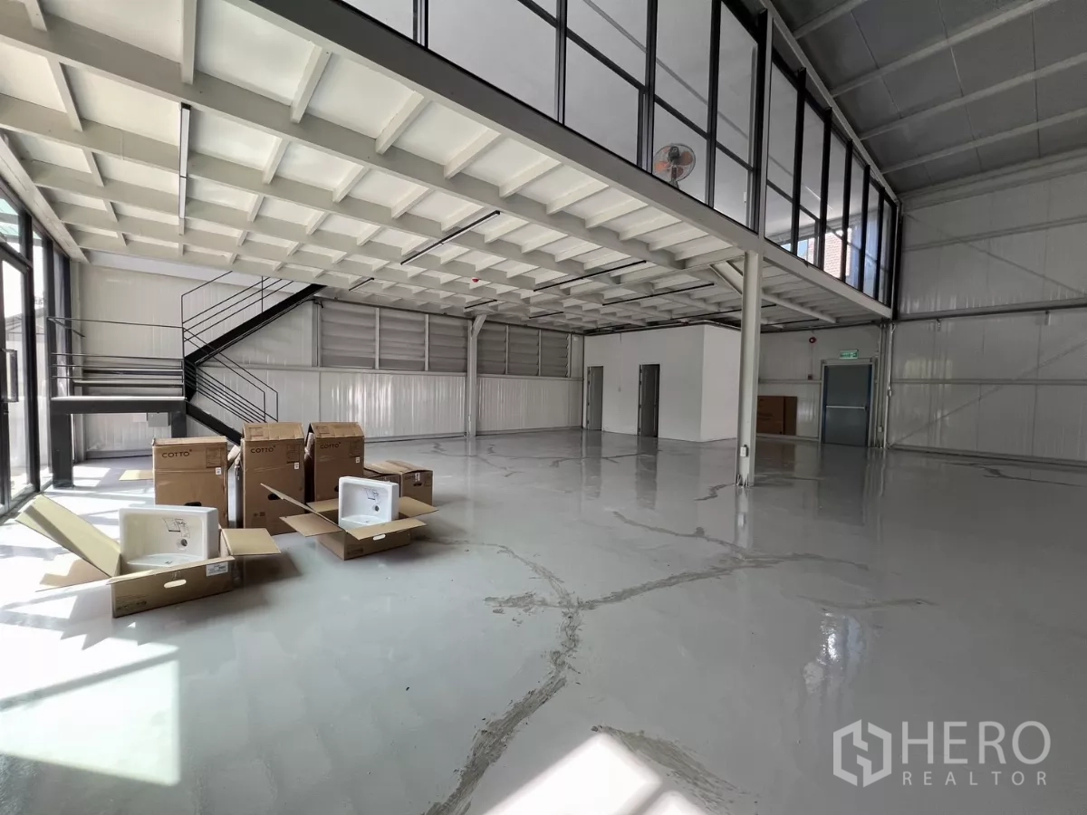 Warehouse for rent in Bang Na, Bangkok - Ground-floor area beneath mezzanine with staircase and boxes, ready for office fit-out.