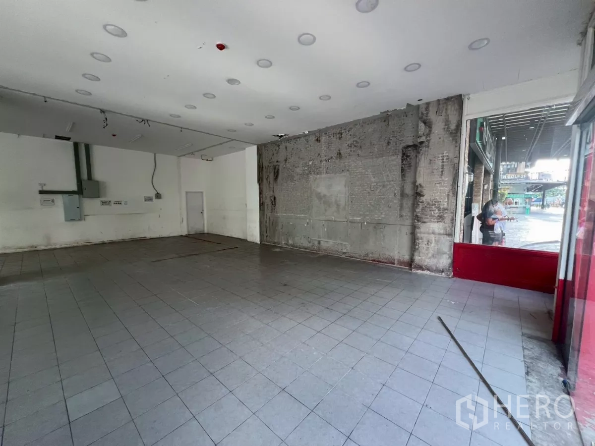 พื้นที่ขายปลีก ให้เช่า - โซนหน้าร้านใกล้ทางเข้า กระจกโชว์สินค้า และผนังดิบพร้อมปรับปรุง