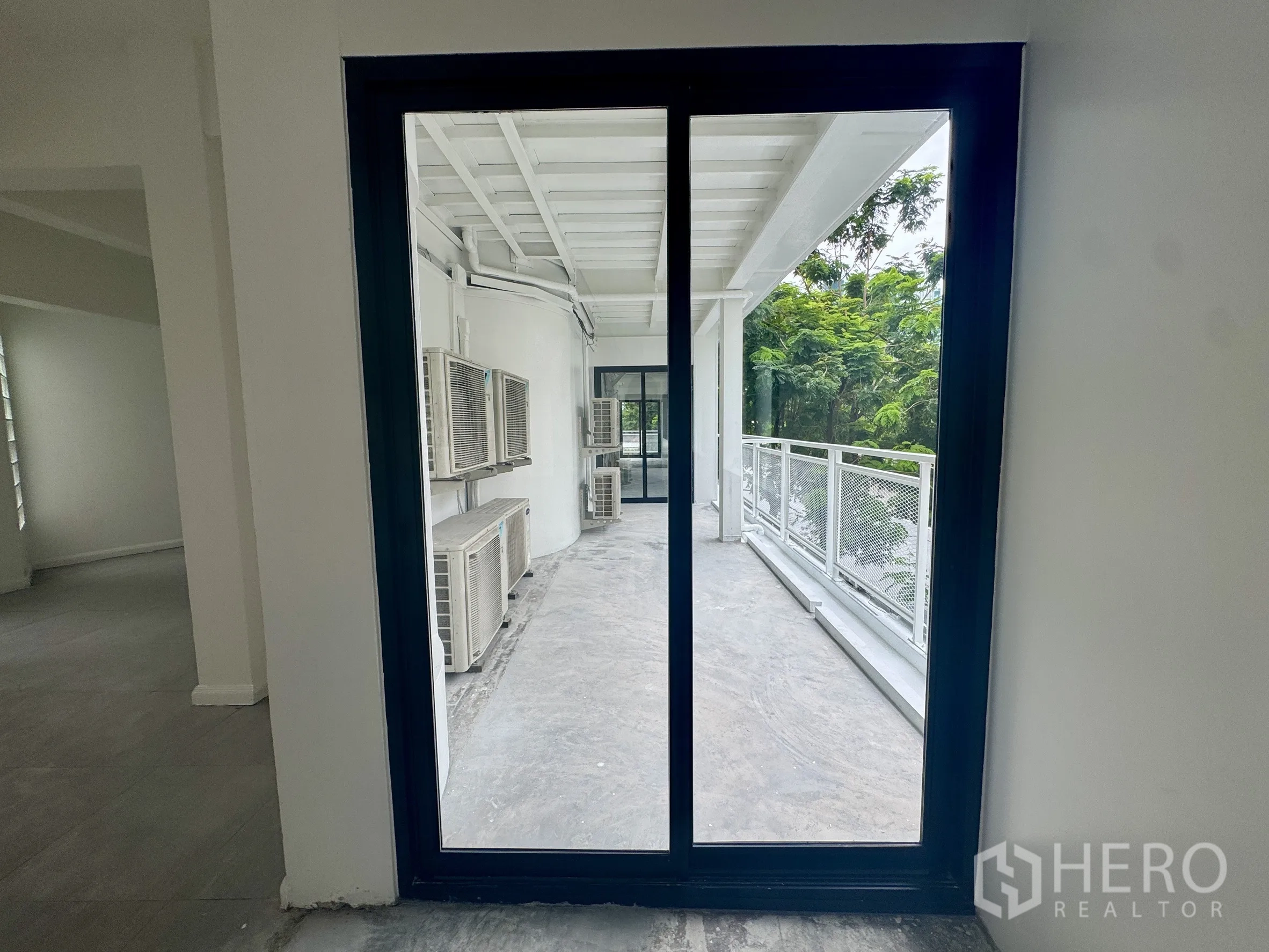 Office Space for rent in Sathon, Bangkok - Sliding door to balcony with AC condenser units and railings amid green trees.