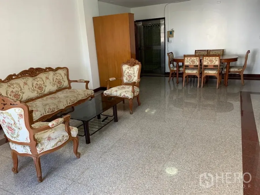Condominium for rent in Sathon, Bangkok - Open-plan lounge and dining area with floral upholstered furniture and glossy stone floors.