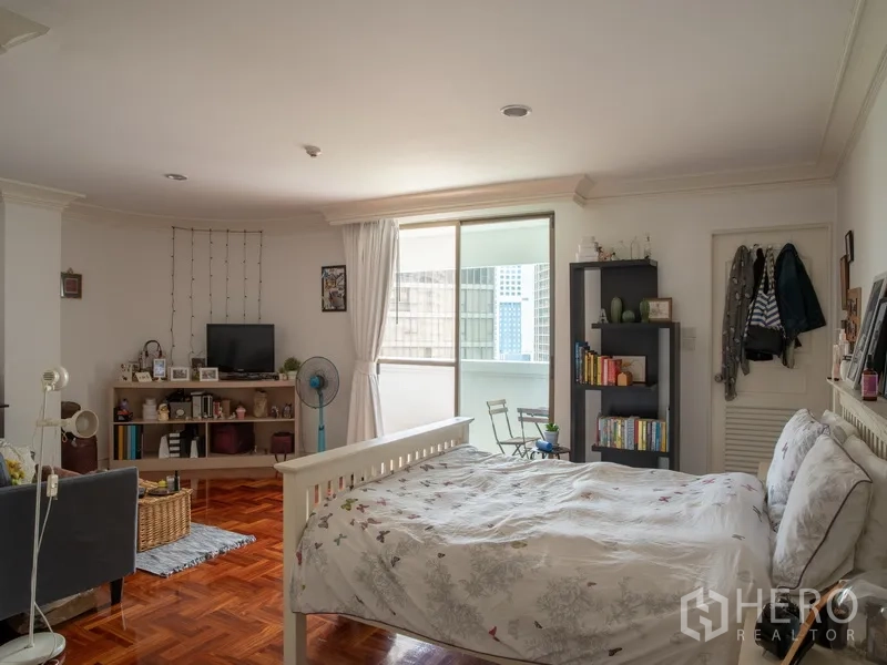Apartment for rent in Khlong Toei, Bangkok - Bright bedroom with balcony access, shelving, and hardwood floor.