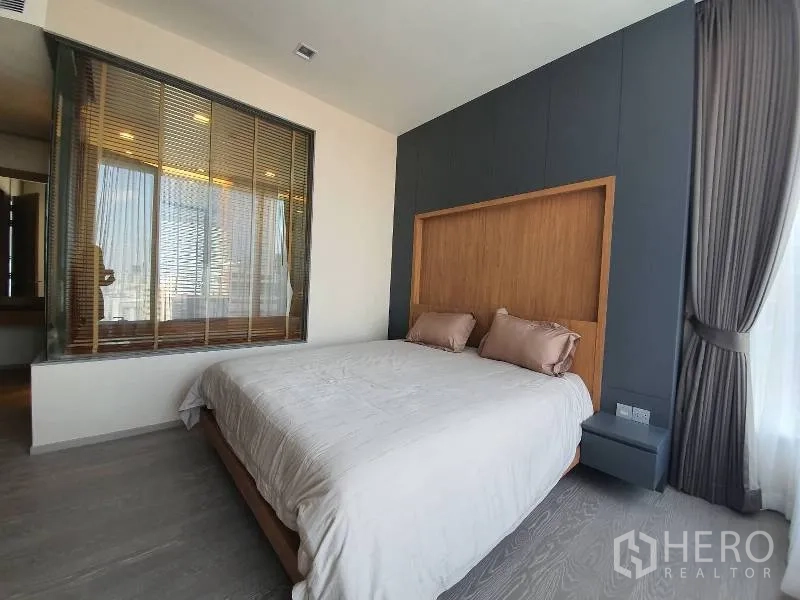 Condominium for rent or sale in Watthana, Bangkok - Master bedroom with feature wood headboard, large window and glass wall opening to the ensuite bathroom.