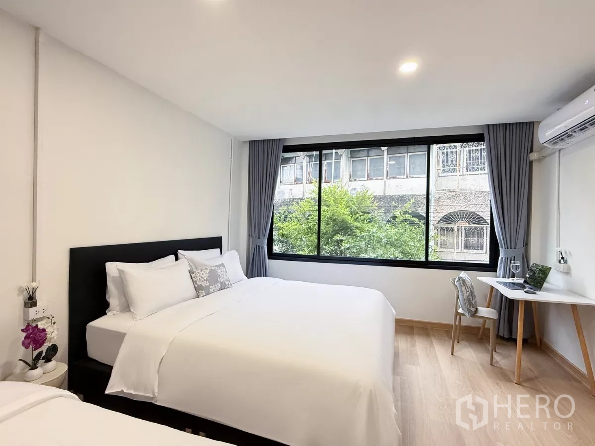 店屋 出租在Ratchathewi, Bangkok - 宽敞卧室，两张床、宽窗与工作台，眺望城市景观。