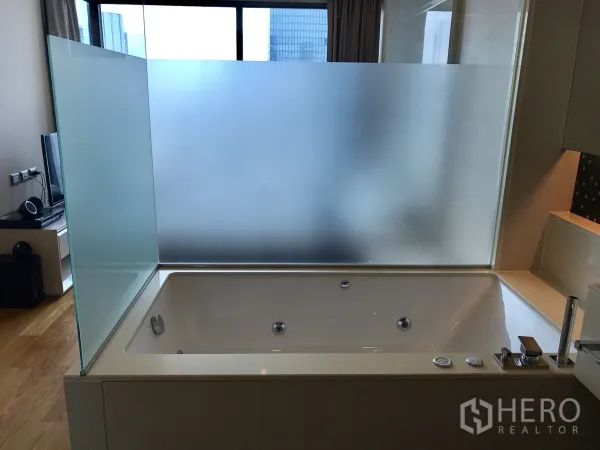 公寓 出租或出售在Bang Rak, Bangkok - 现代浴室内的大型浸泡浴缸，配磨砂玻璃隔断。
