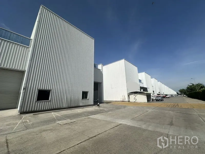 工厂 出租在Khlong Luang, Pathum Thani - 12米宽通道，两侧整齐的白色厂房与装卸区。