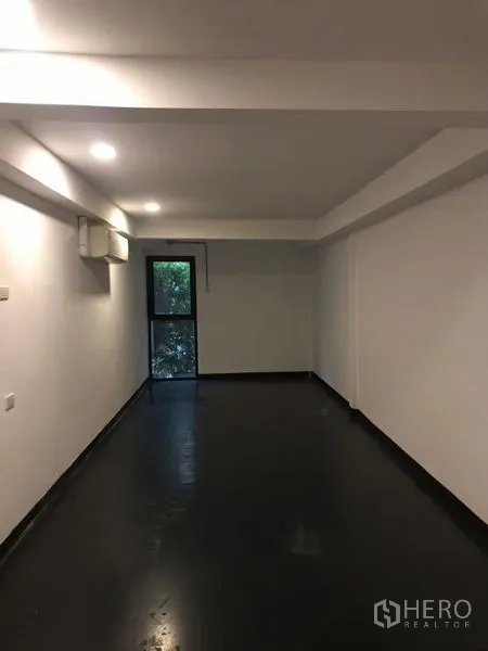 Home Office for rent or sale in Khlong Toei, Bangkok - Square room with dark floor, white walls and full-height curtains covering a sliding door.