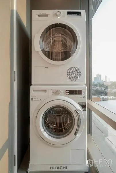 คอนโด ให้เช่าในSathon, Bangkok - เครื่องซักผ้าและเครื่องอบผ้าวางซ้อนกันข้างหน้าต่างสูงมองเห็นวิวเมือง