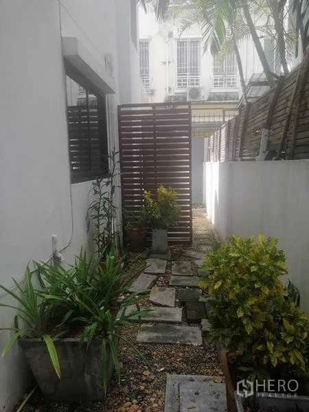 Townhouse for rent in Wang Thonglang, Bangkok - Narrow side garden with potted plants, stepping stones and a privacy screen.