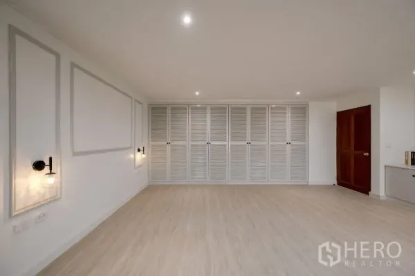 Condominium for sale - Spacious room featuring full-wall louvered closets and a wooden door.