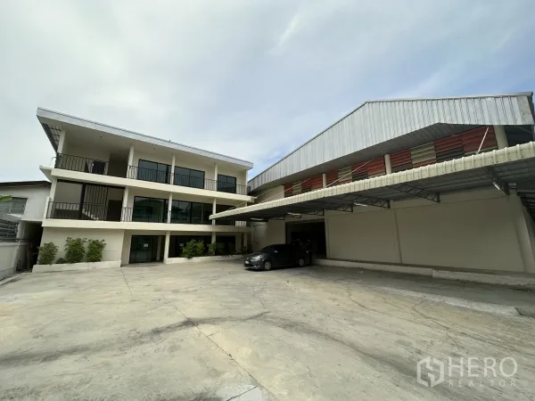 货栈 出租在Suan Luang, Bangkok - 宽阔水泥院子，三层办公楼与带顶装卸区的曼谷仓库外观。