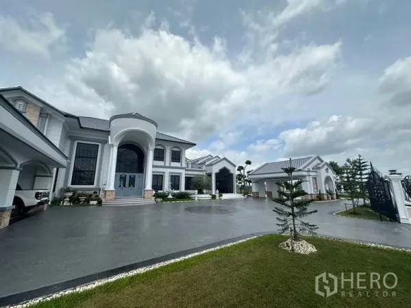 Detached House for sale in Sai Noi, Nonthaburi - Front courtyard with porte-cochère, expansive driveway and manicured trees.