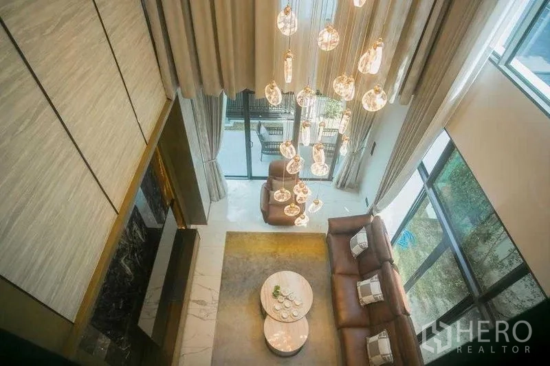 Detached House for rent in Bangkok - Aerial view of the living room showing statement chandelier, sofa set and large sliding doors.