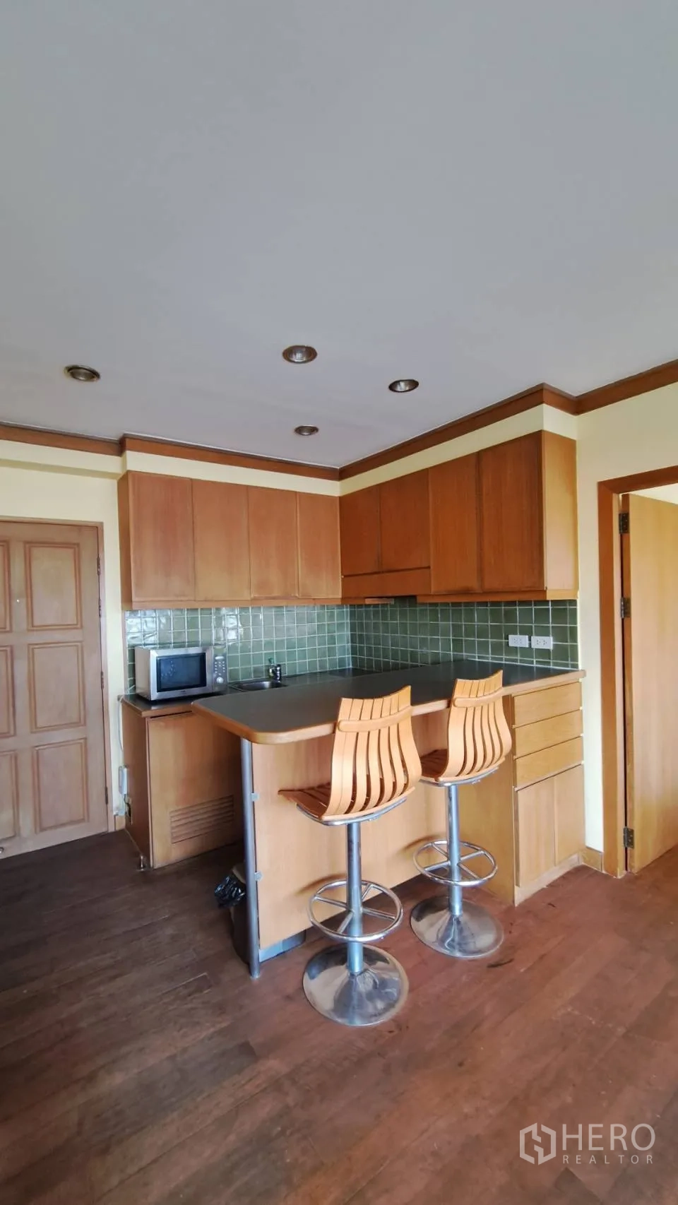 Condominium for rent in Khlong Toei, Bangkok - Breakfast bar with two stools beside the built-in wooden kitchen.