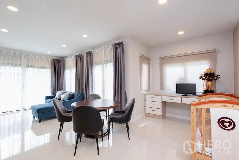 独立式住宅 出租在Bang Phli, Samut Prakan - 客餐厅一角，蓝色沙发、圆桌与书桌。