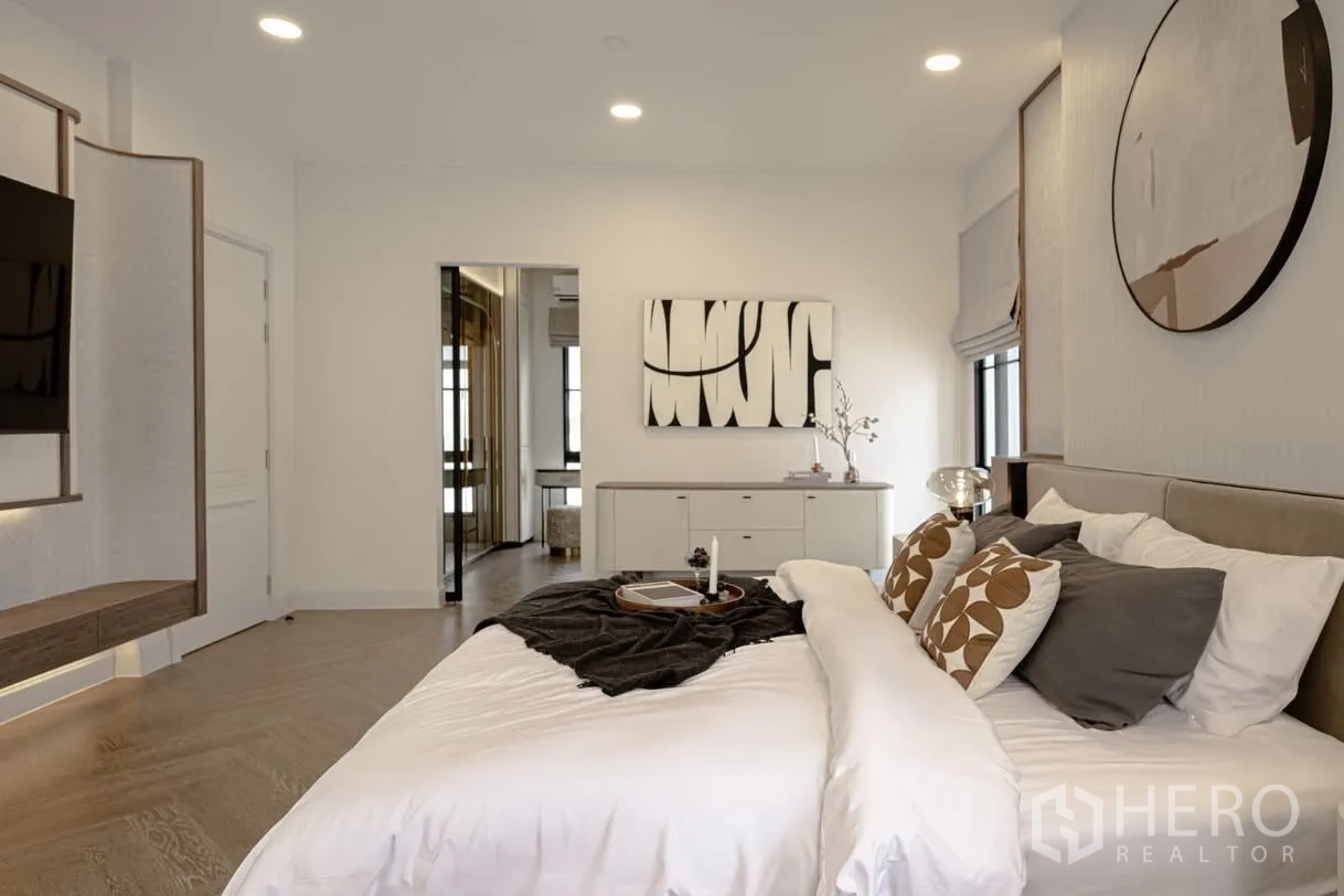 บ้านเดี่ยว for rent in Saphan Sung, Bangkok - ห้องนอนใหญ่ตกแต่งโมเดิร์น เตียงคิง ทีวีติดผนัง พื้นไม้ และงานศิลป์