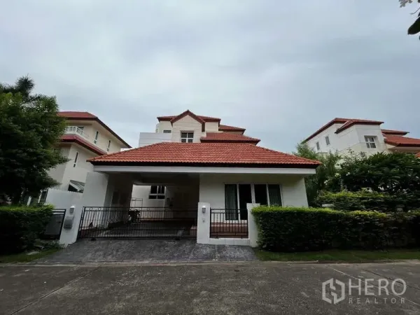 บ้าน ให้เช่าในPrawet, Bangkok - ด้านหน้าบ้านเดี่ยวให้เช่าในเขตประเวศ กรุงเทพฯ หลังคากระเบื้องสีแดง พร้อมประตูรั้วและที่จอดรถ.