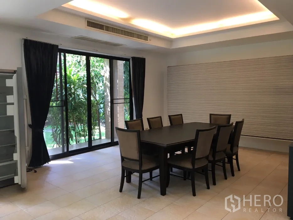 Detached House for rent in Watthana, Bangkok - Dining room with eight-seat table, recessed ceiling lighting and floor-to-ceiling glass to the garden.