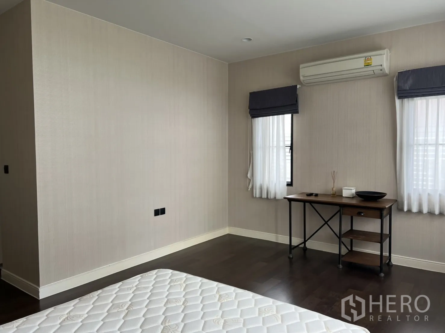 Detached House for rent or sale in Bang Kapi, Bangkok - Master bedroom corner with work desk, two windows and air-conditioning unit.