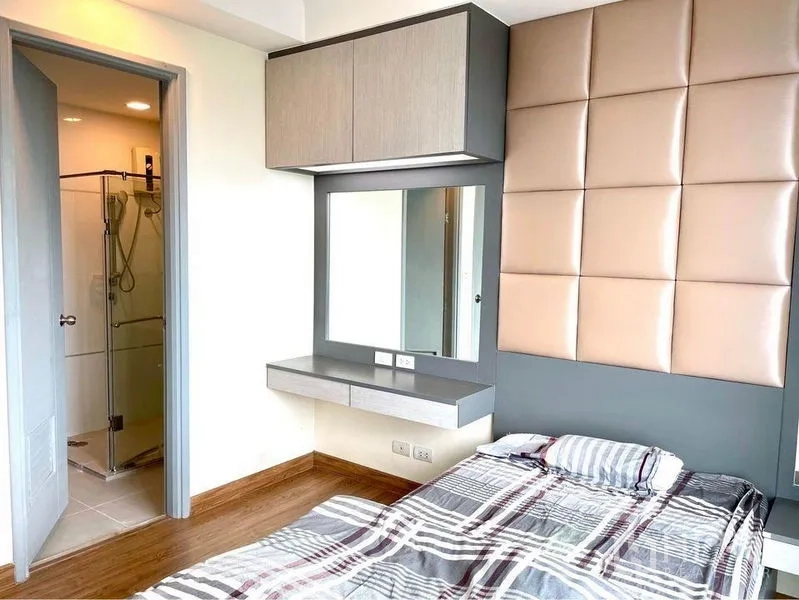 Condominium for rent in Huai Khwang, Bangkok - Second bedroom with padded headboard, built-in vanity and ensuite shower.