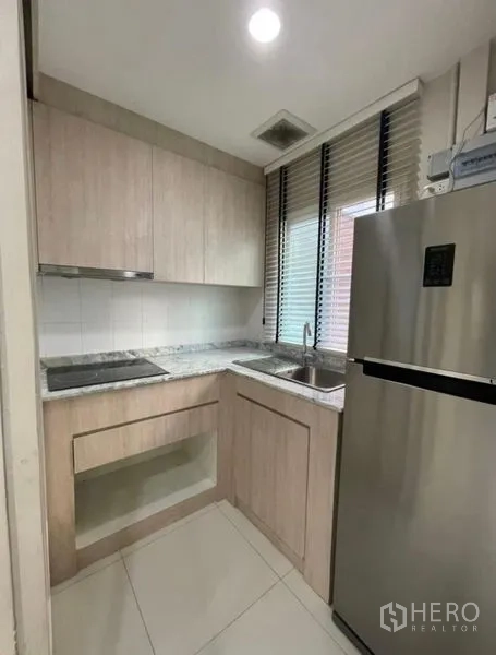 ทาวน์เฮาส์ ขาย - ครัวรูปตัวแอลขนาดกะทัดรัด ตู้ไม้สีอ่อน เคาน์เตอร์หิน ซิงก์ เตา และตู้เย็นสแตนเลส