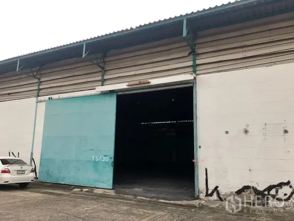 货栈 出租在Bang Phli, Samut Prakan - 仓库正面带大型青色滑动门与混凝土装卸区。