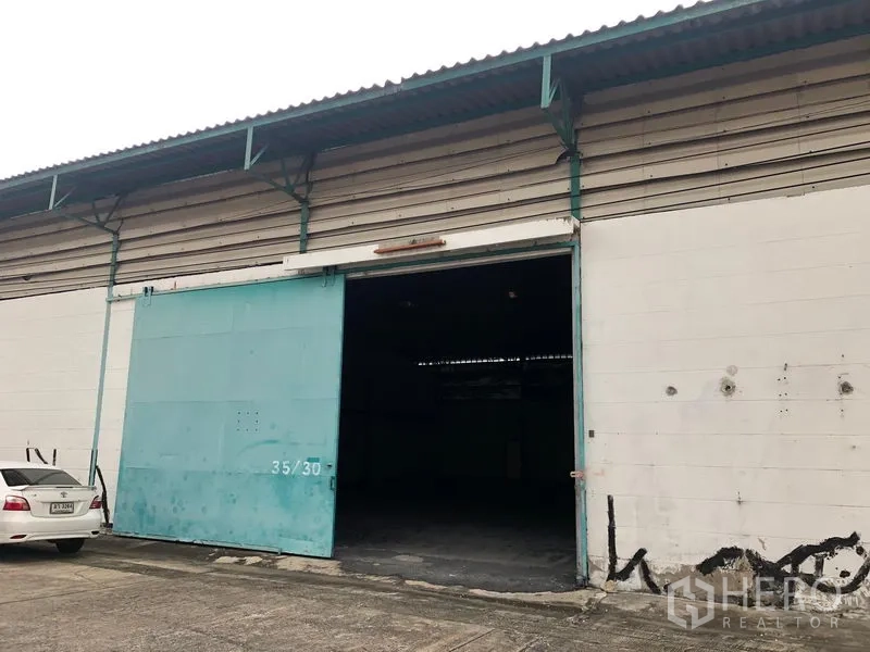 货栈 出租在Bang Phli, Samut Prakan - 仓库正面带大型青色滑动门与混凝土装卸区。