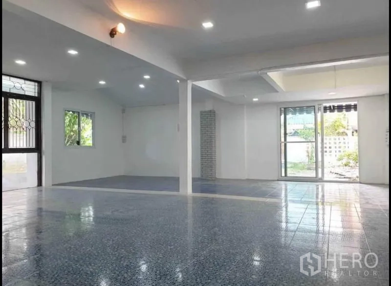 บ้าน ให้เช่าในLat Phrao, Bangkok - โถงกว้างติดไฟดาวน์ไลต์ พื้นกระเบื้องลาย และประตูกระจกบานเลื่อนออกสู่สวน